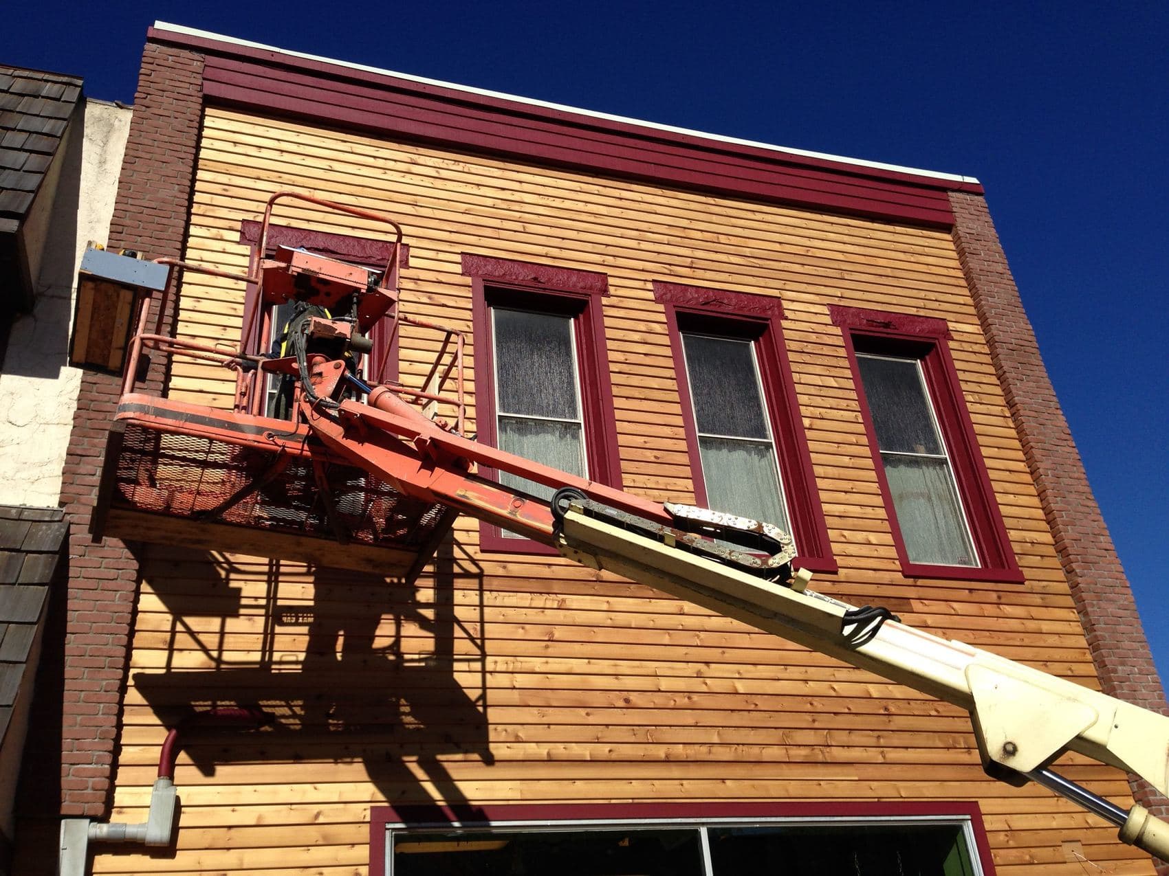 Crew on a lift installing siding on a commercial building