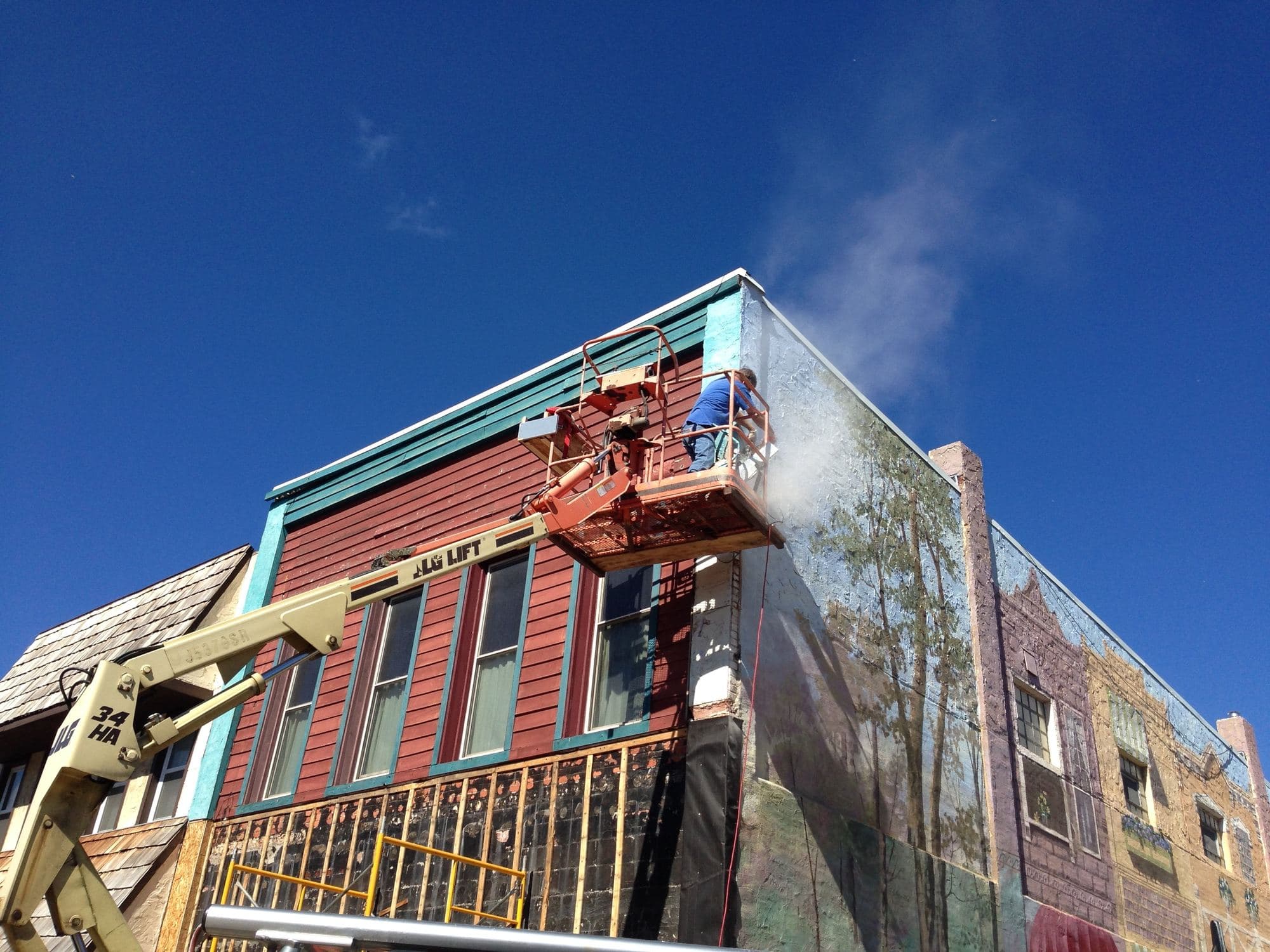 Washing and repainting the exterior of a downtown building from a lift